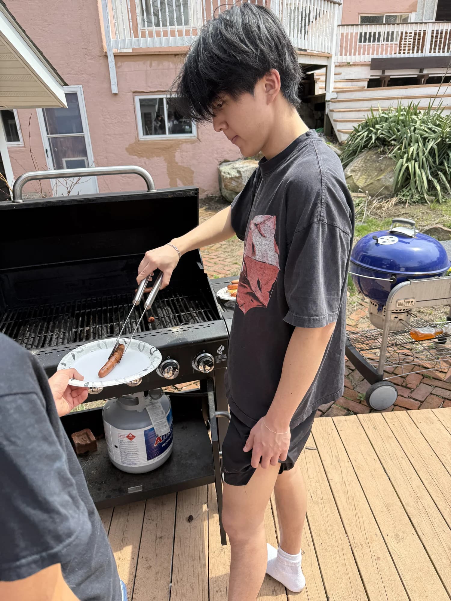 A member turning sausages on a backyard grill