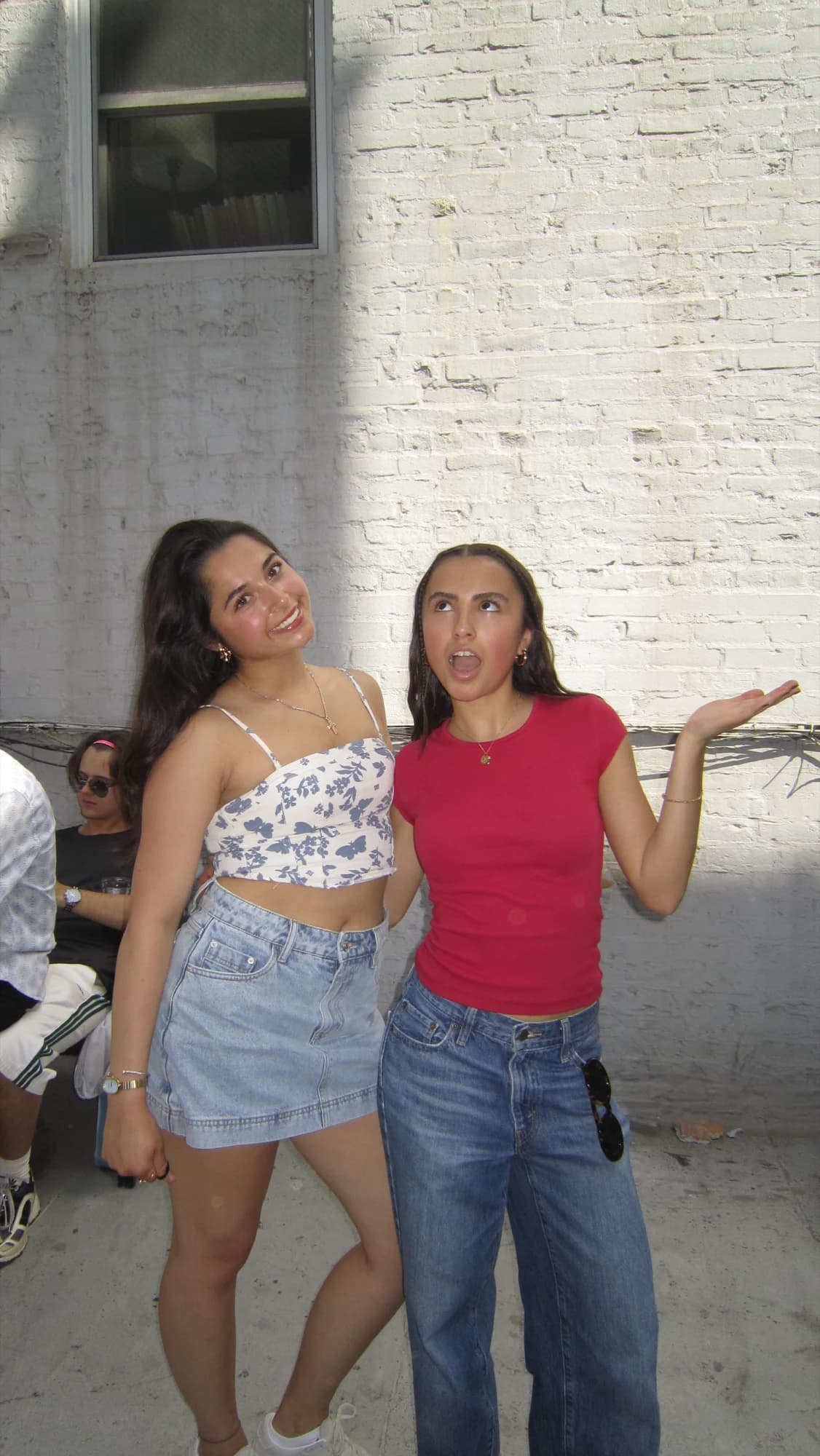Two members posing against a white brick wall in the sun
