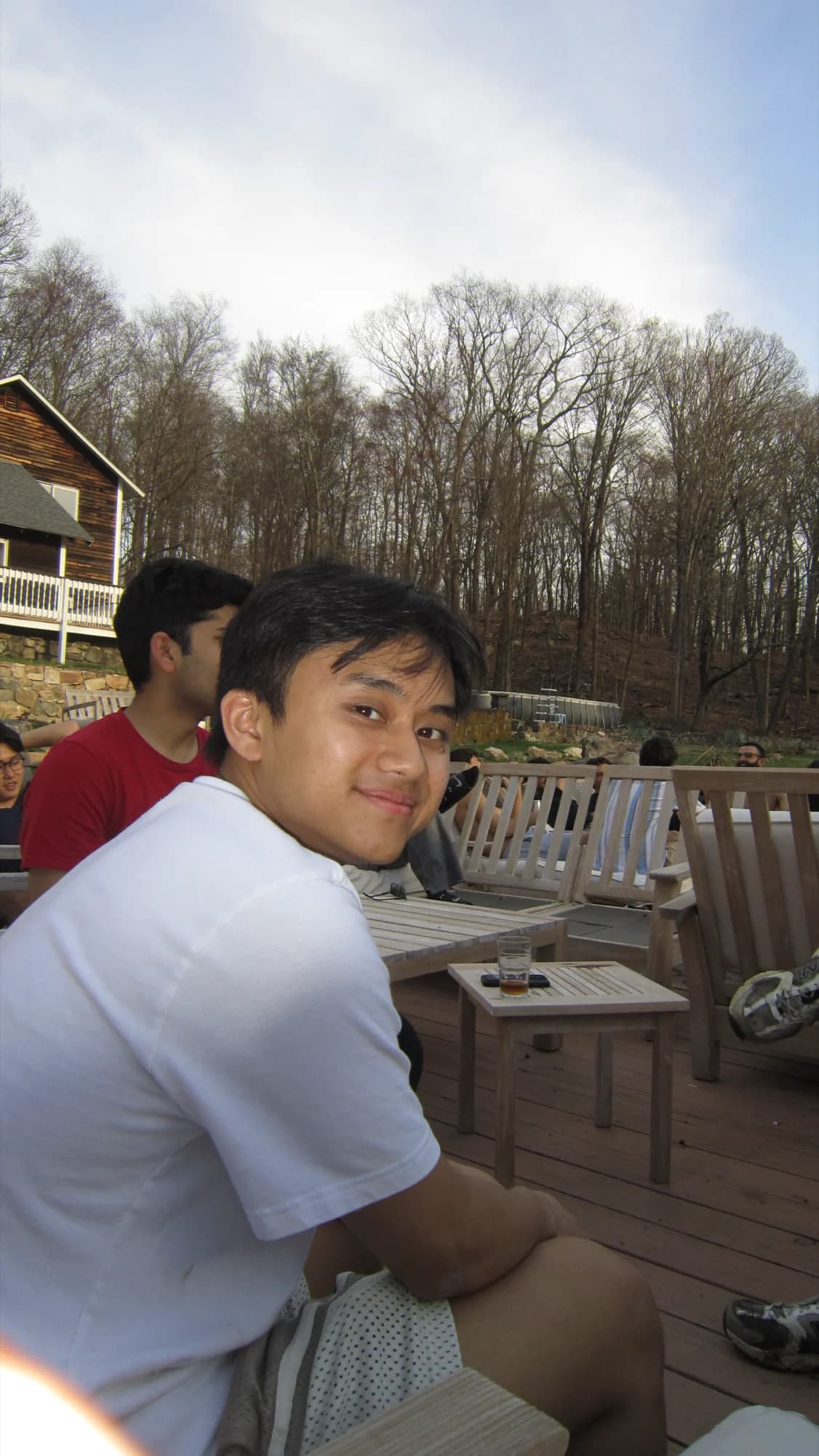 A member turning back to the camera from a deck chair, woods behind