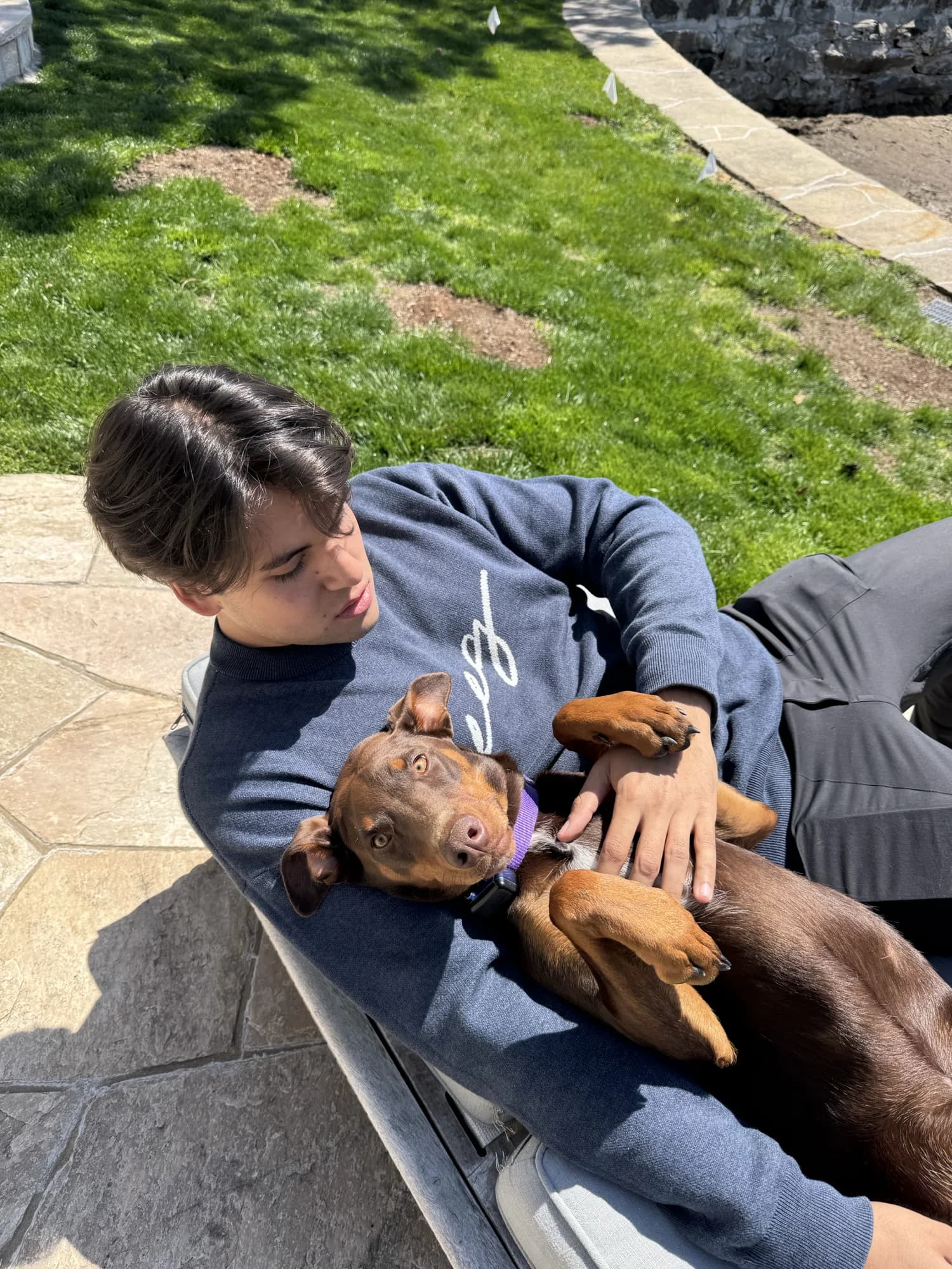 A member lying on a stone wall with a dog stretched across his chest