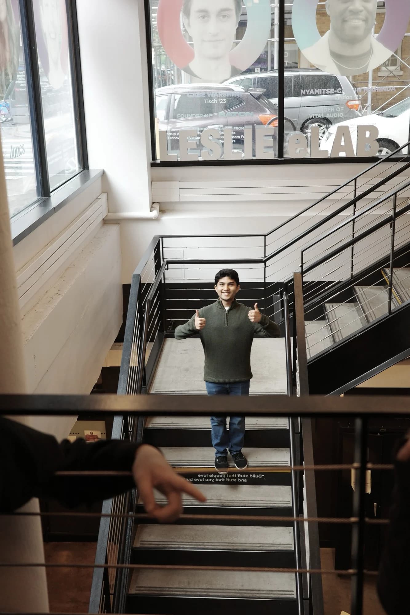 A member giving two thumbs up on a staircase beneath a Leslie eLAB sign