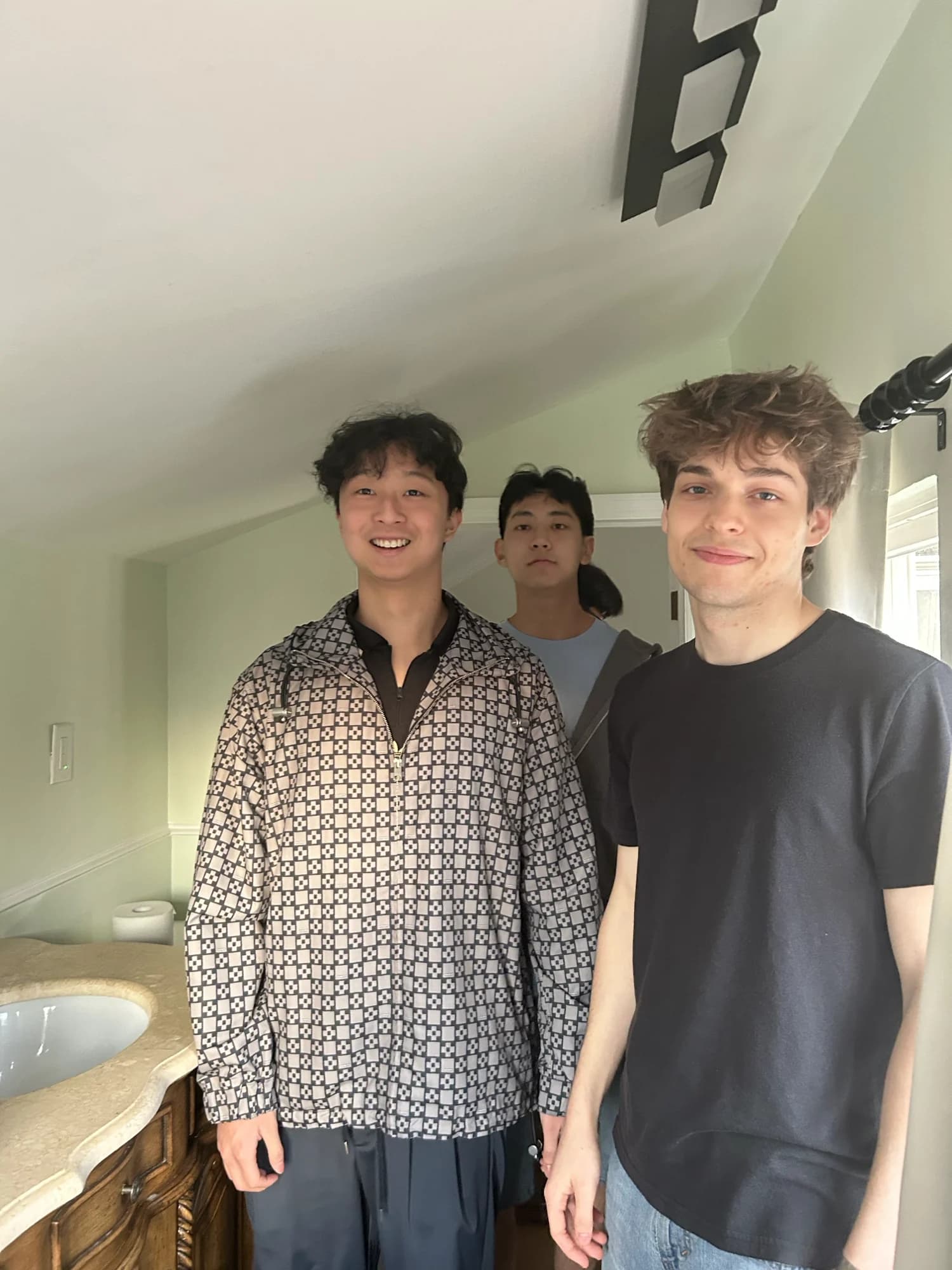 Three members posing together in a narrow hallway