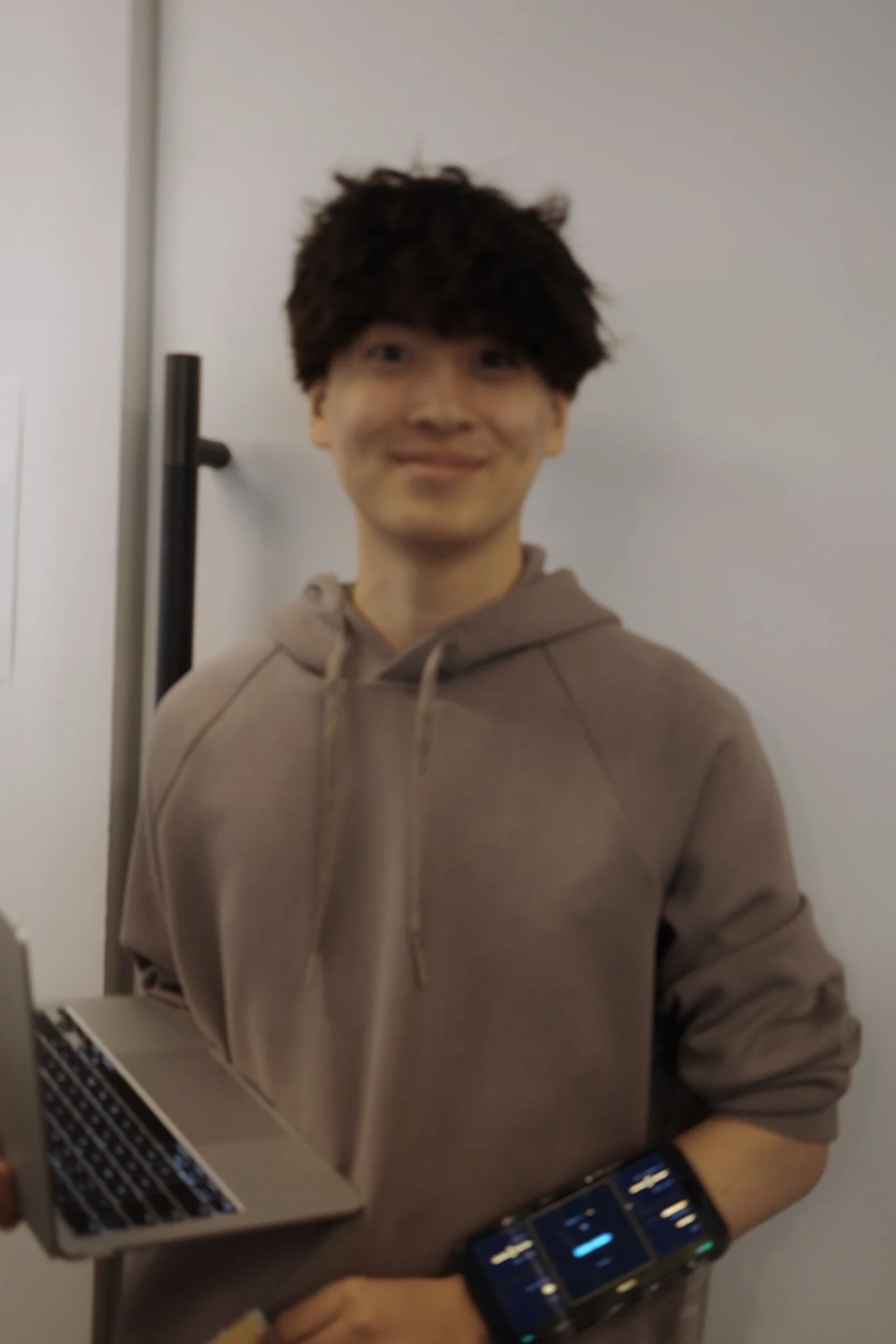 A member in a tan hoodie smiling for the camera
