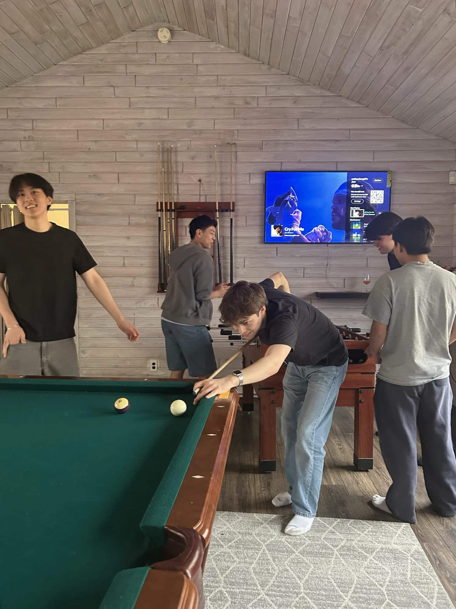 Members playing pool and foosball in a wood-panelled game room