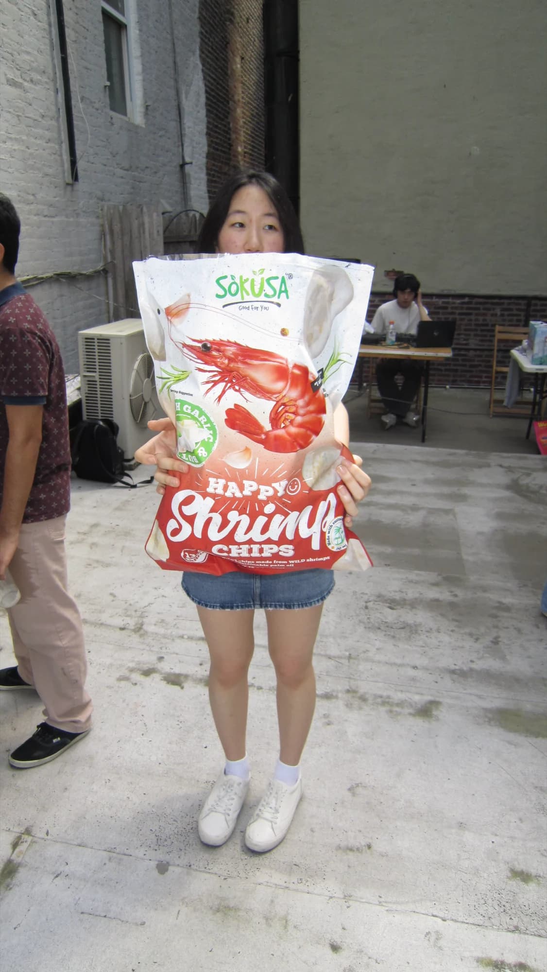 A member holding an enormous bag of shrimp chips in front of her