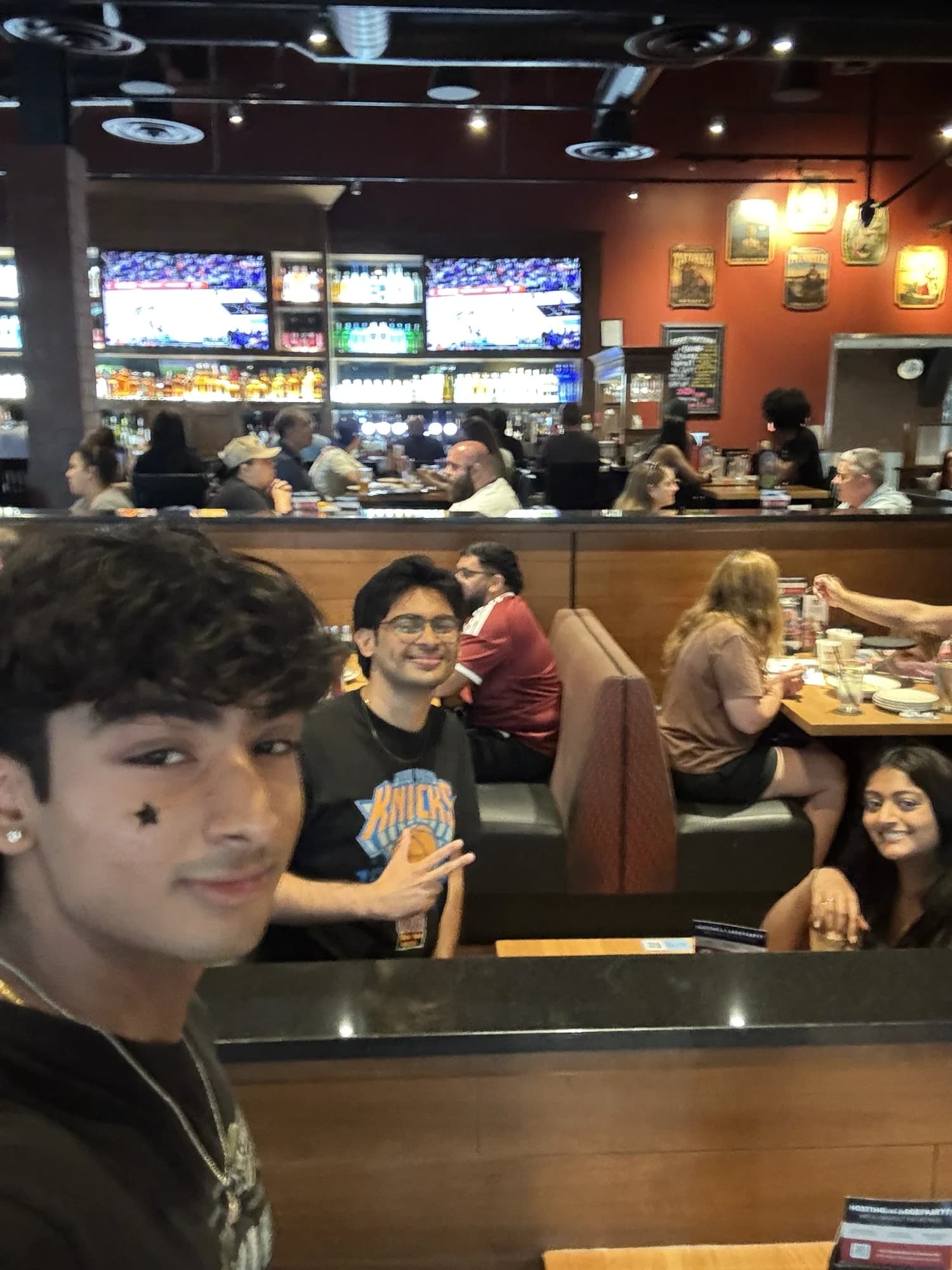 Members in a sports bar, one in a Knicks jersey pointing at the camera